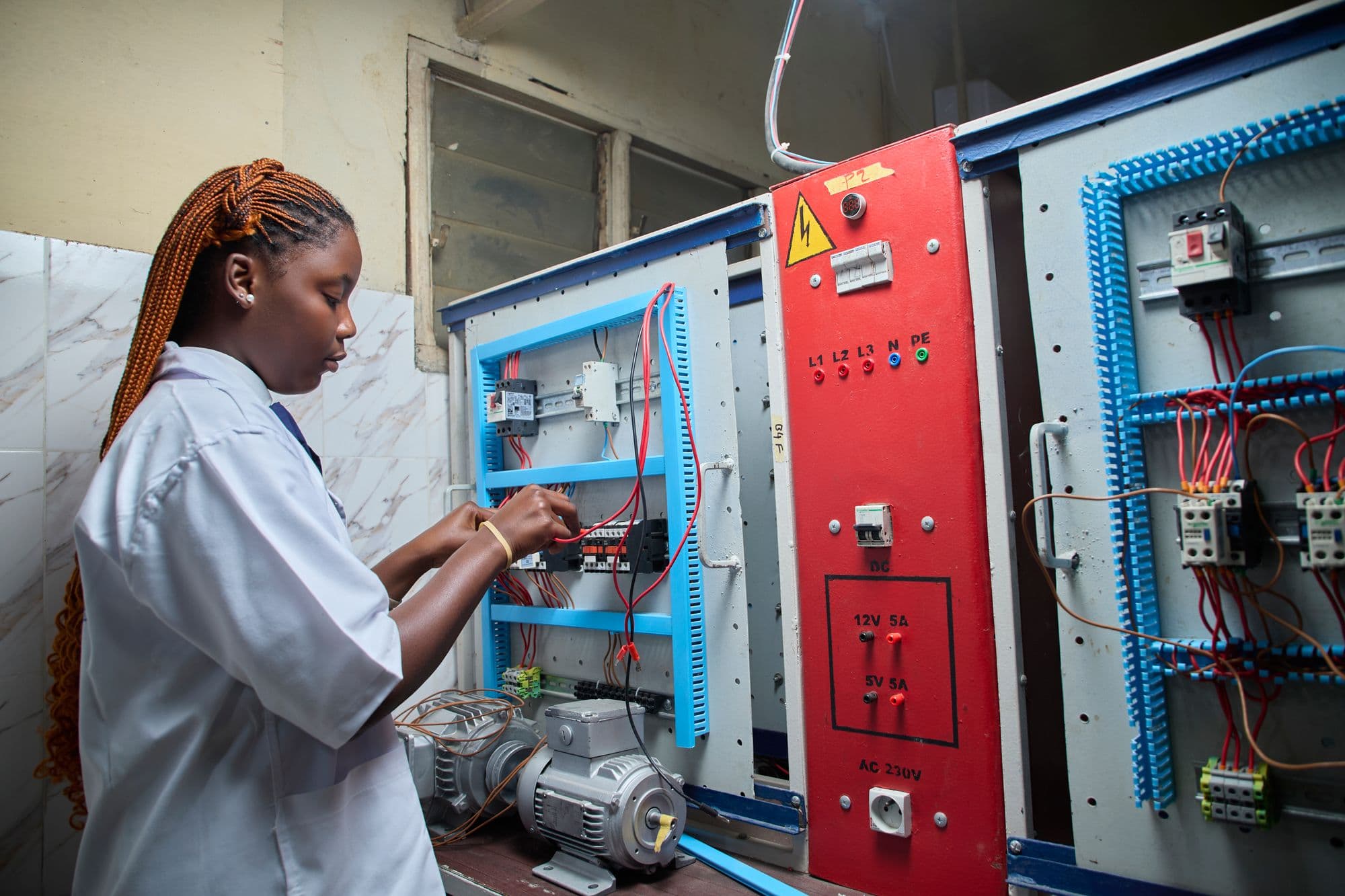 A technician wiring an electrical control panel during practical training
