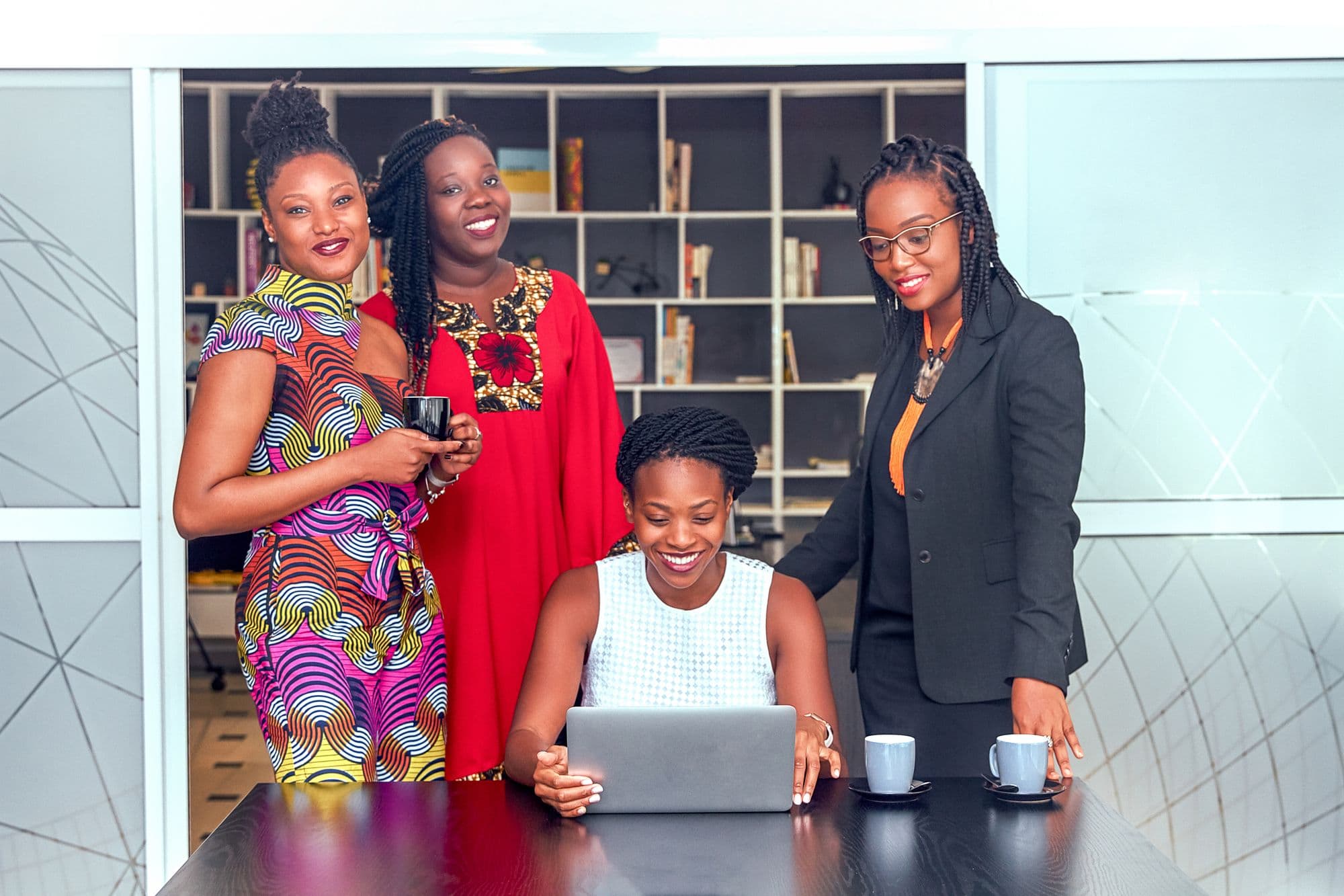 Professional women collaborating around a laptop
